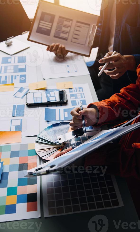 Close up ux developer and ui designer brainstorming about mobile app interface wireframe design on table with customer breif and color code at modern office.Creative digital development agency photo