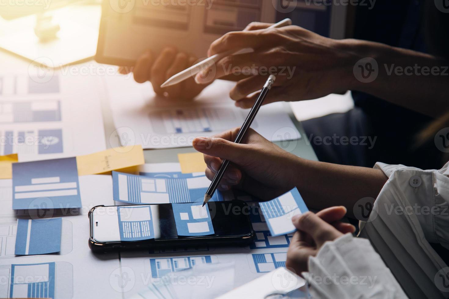 Close up ux developer and ui designer brainstorming about mobile app interface wireframe design on table with customer breif and color code at modern office.Creative digital development agency photo