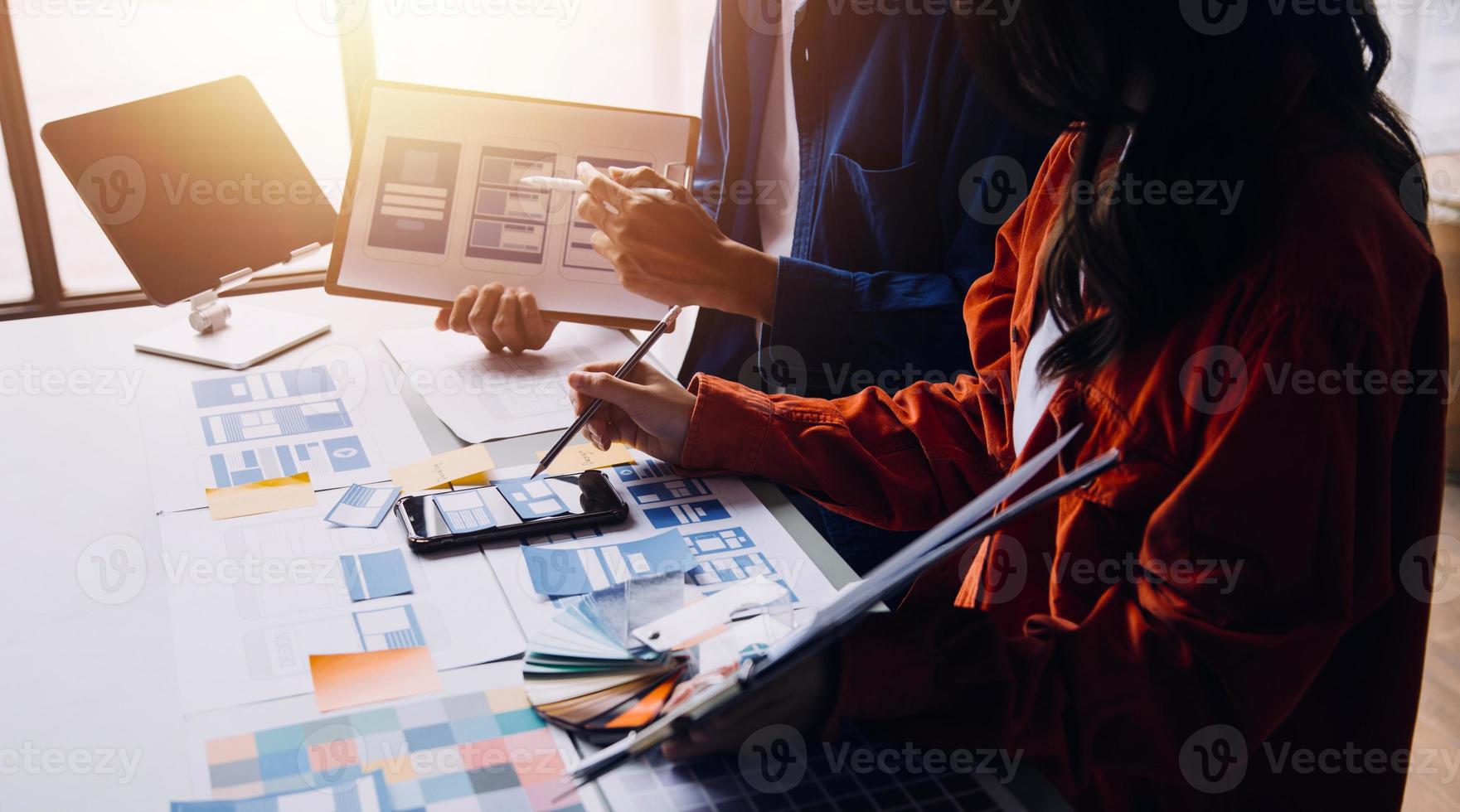 Close up ux developer and ui designer brainstorming about mobile app interface wireframe design on table with customer breif and color code at modern office.Creative digital development agency photo