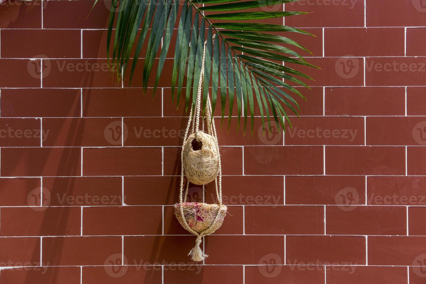 Handmade birds nest are hanging on the bricks wall. Interior Decoration Design. Nest made of fiber. photo