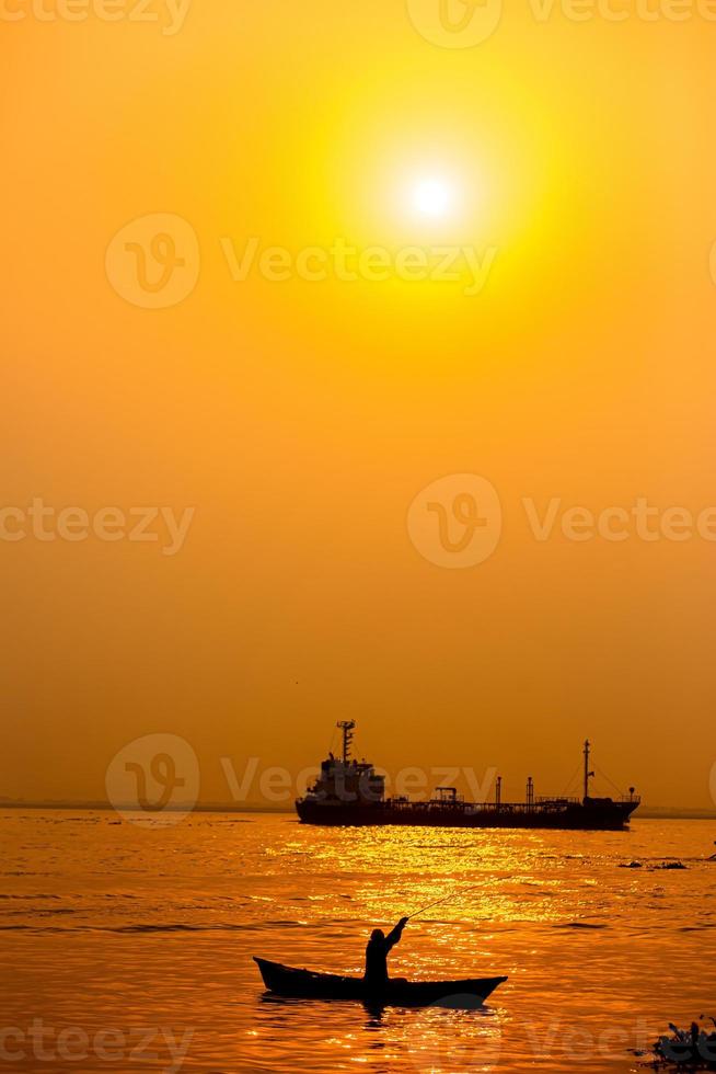 Evening golden sunset time, a fisherman fishing on the seaside on a boat. photo