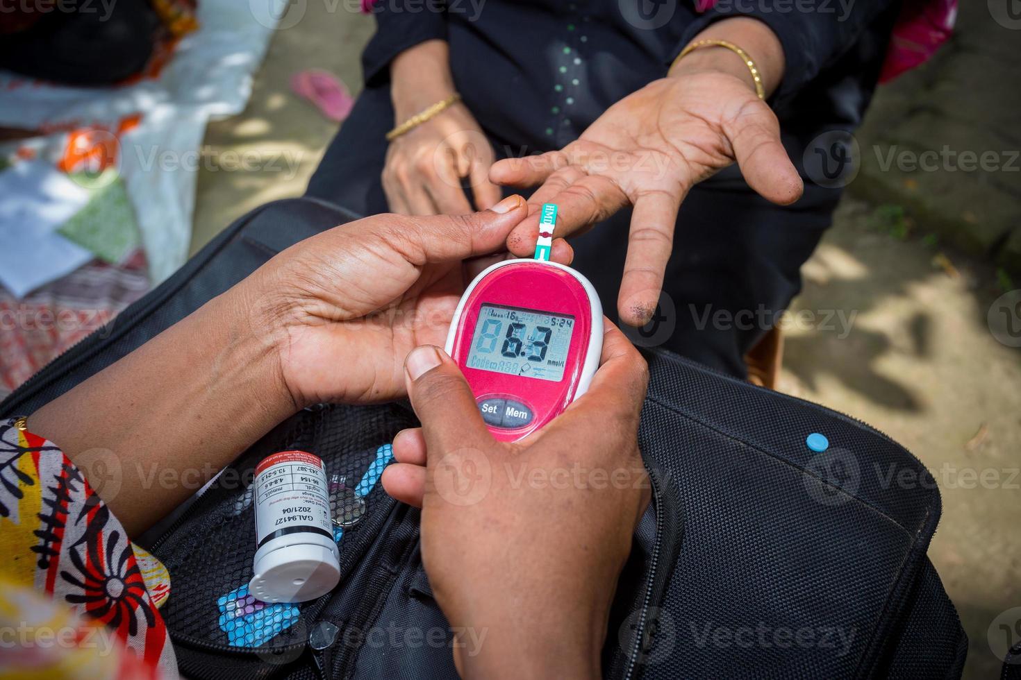 Woman checking sugar level with glucometer using a blood sample at Narsingdi, Bangladesh. Learn to use a glucometer. Concept of diabetes treatment. photo