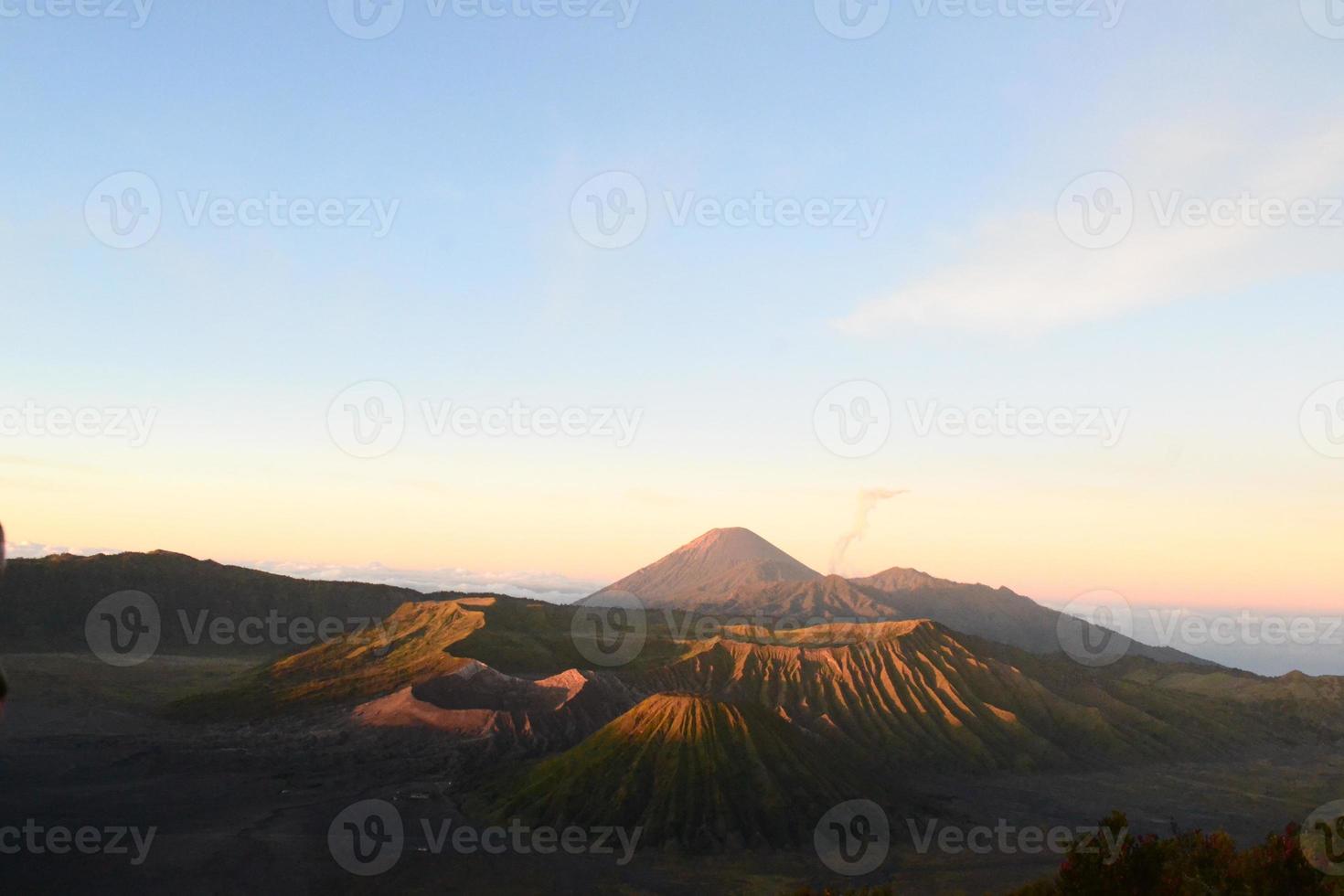 View of Mount Bromo in the morning with the peaks of Mount Semeru in the background photo