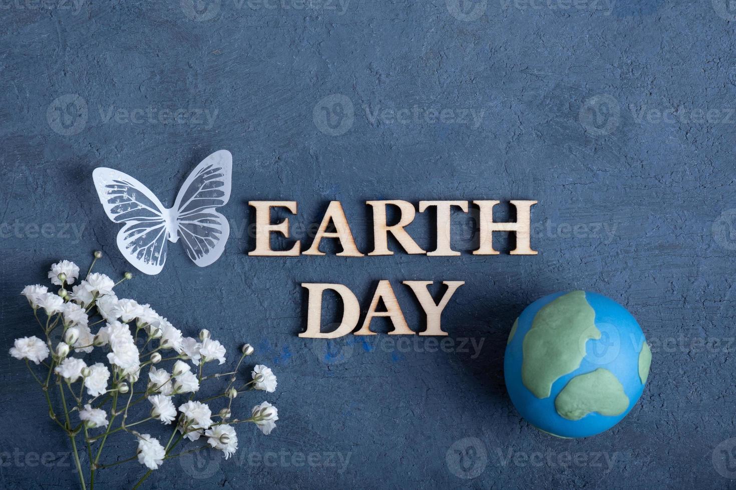 Earth day text with globe, flowers and butterfly. Happy Earth day concept flat lay, top view photo