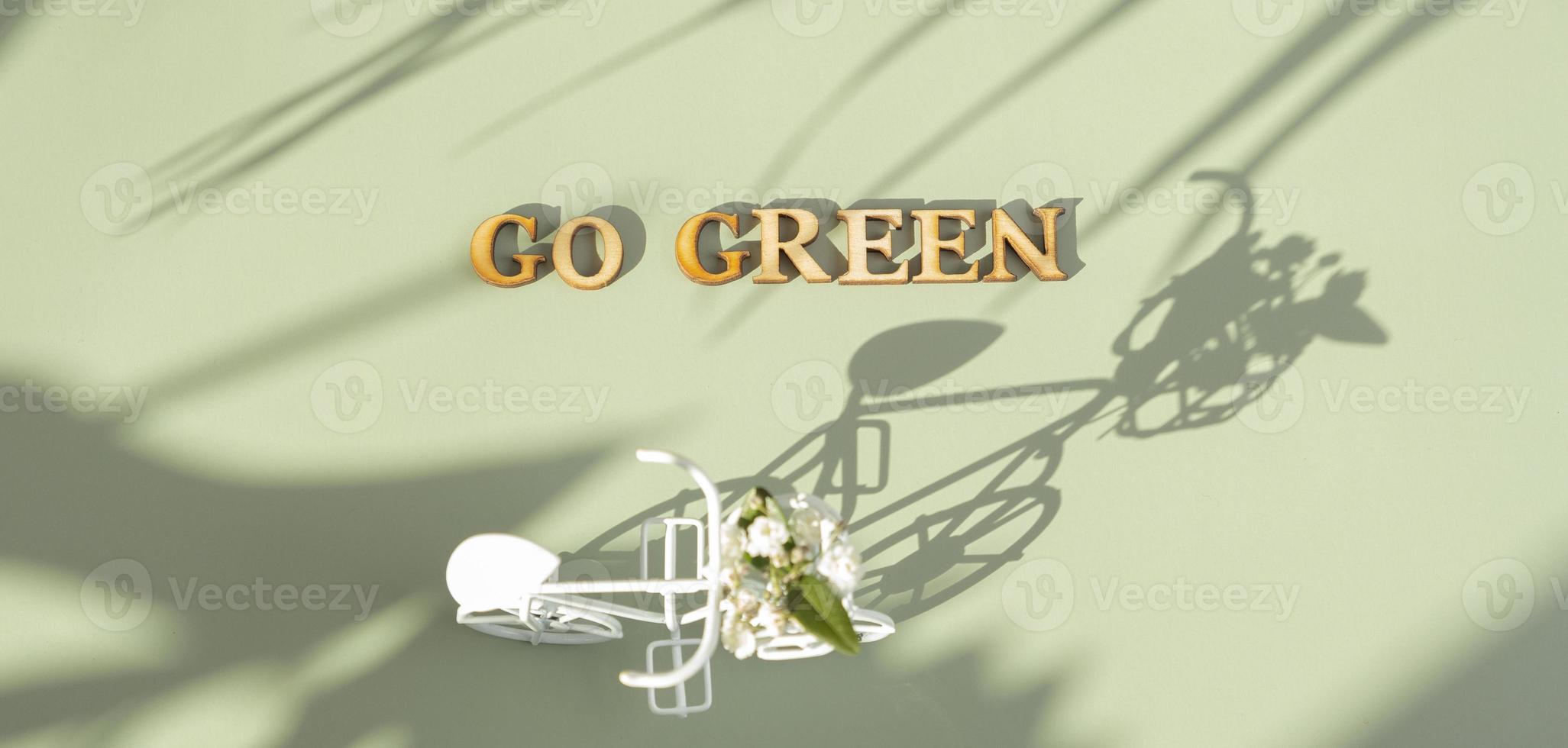 Go green text with bycicle on green background with hard shadows. Sustainable lifestyle concept photo