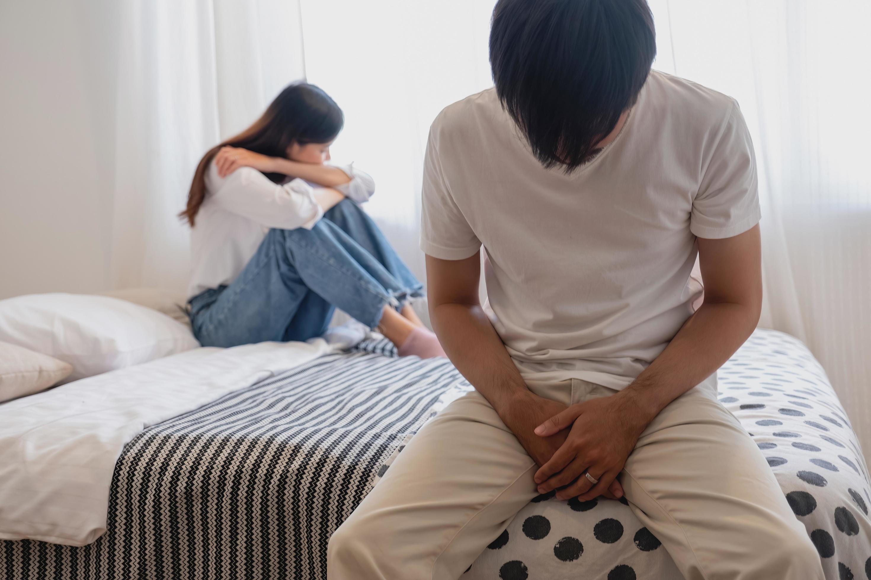 The husband is unhappy and disappointed in the erectile dysfunction during sex while his wife sleeping on the picture