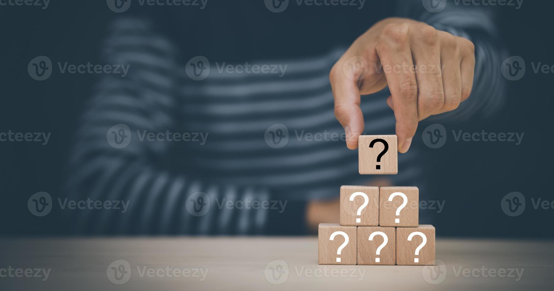 Hand hold Wooden cube block in question mark mean what on cement table background, column of wooden blocks with question sign mark. copy space,FAQ frequently asked questions, Answer, Information photo