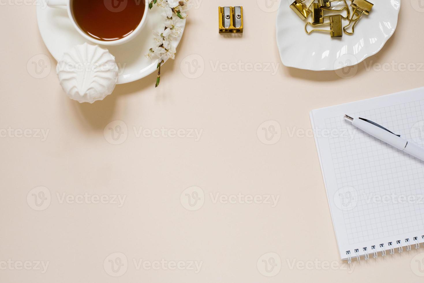 Work desk of a modern woman, home office. Notepad, tea, spring apple flowers on a light table. Minimal business concept, flat lay, place for text. photo