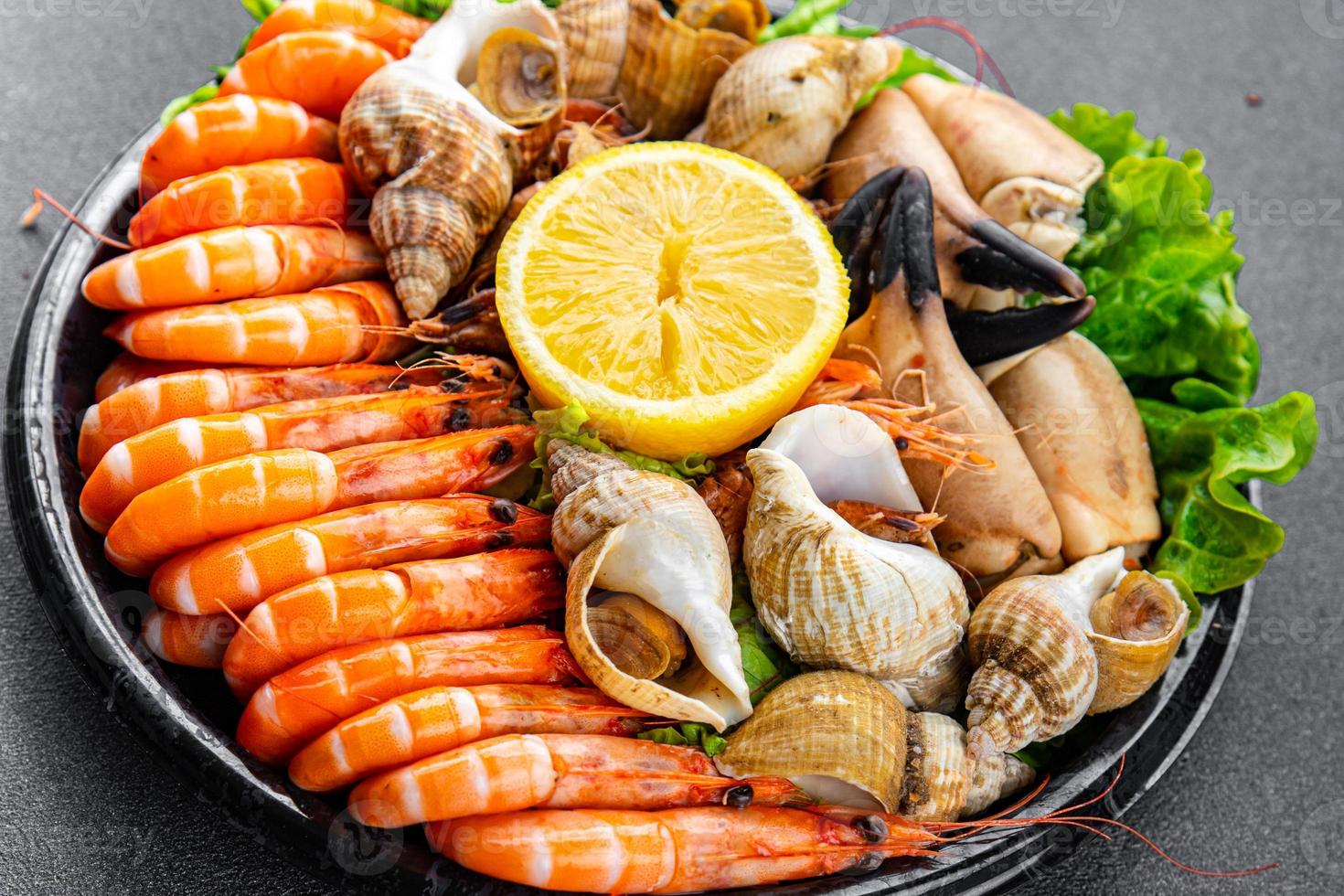 seafood plate assorted shrimps, crab claws, clams, rapan, trumpeter mollusk meal food snack on the table copy space food background rustic top view photo