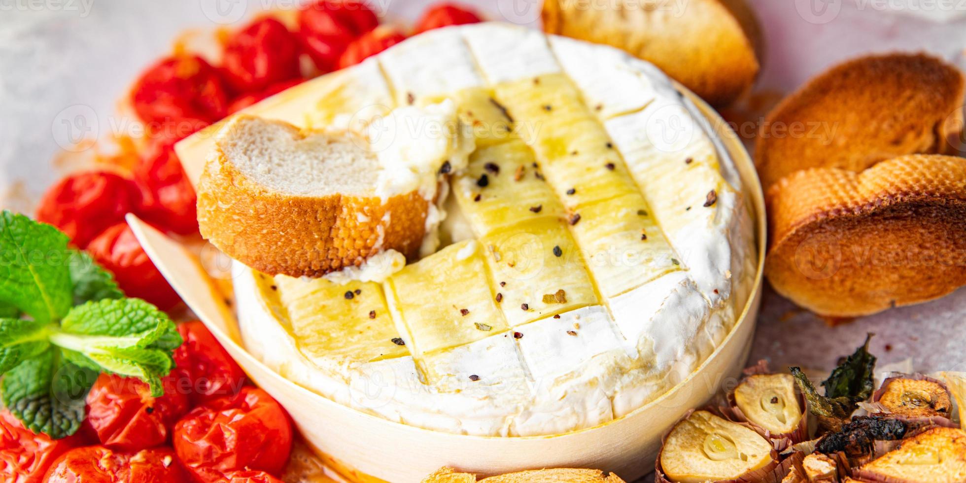 horneado suave queso queso Brie o queso Camembert tomate, ajo y hierbas comida comida bocadillo en el mesa Copiar espacio comida antecedentes rústico parte superior ver foto