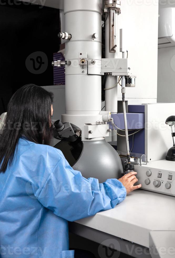 Young female scientist working at the laboratory with an electron microscope photo