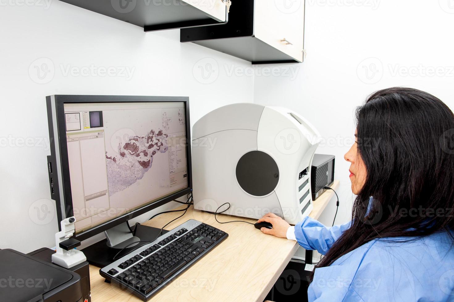 Young female scientist scanning microscope slides with tissue samples for pathology studies. Cancer diagnosis concept. Medical technology concept. photo