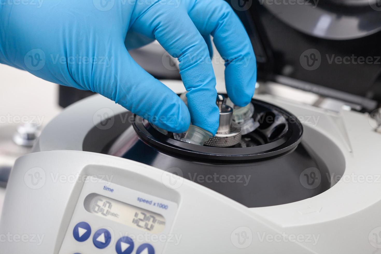 Closeup of a scientist hand placing a tube into an small table centrifuge. Spin column-based nucleic acid purification technique. photo
