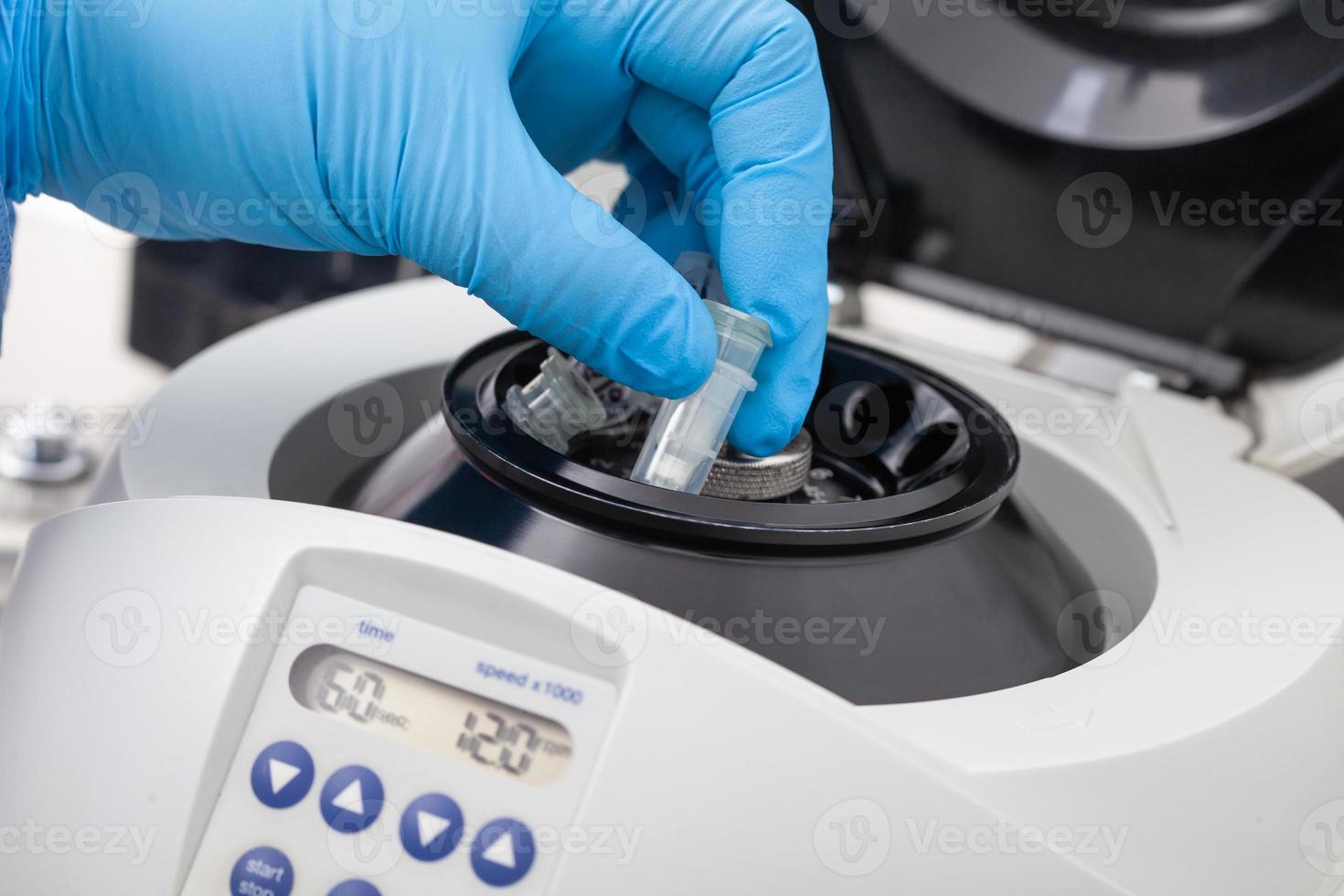 Closeup of a scientist hand placing a tube into an small table centrifuge. Spin column-based nucleic acid purification technique. photo