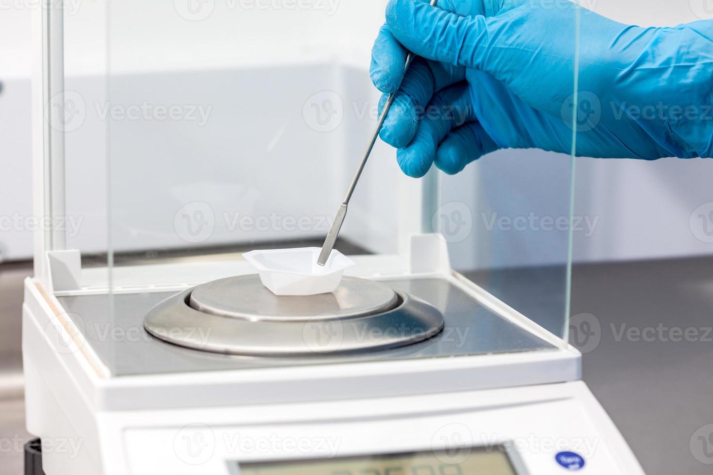 Scientist using an analytical balance at laboratory photo