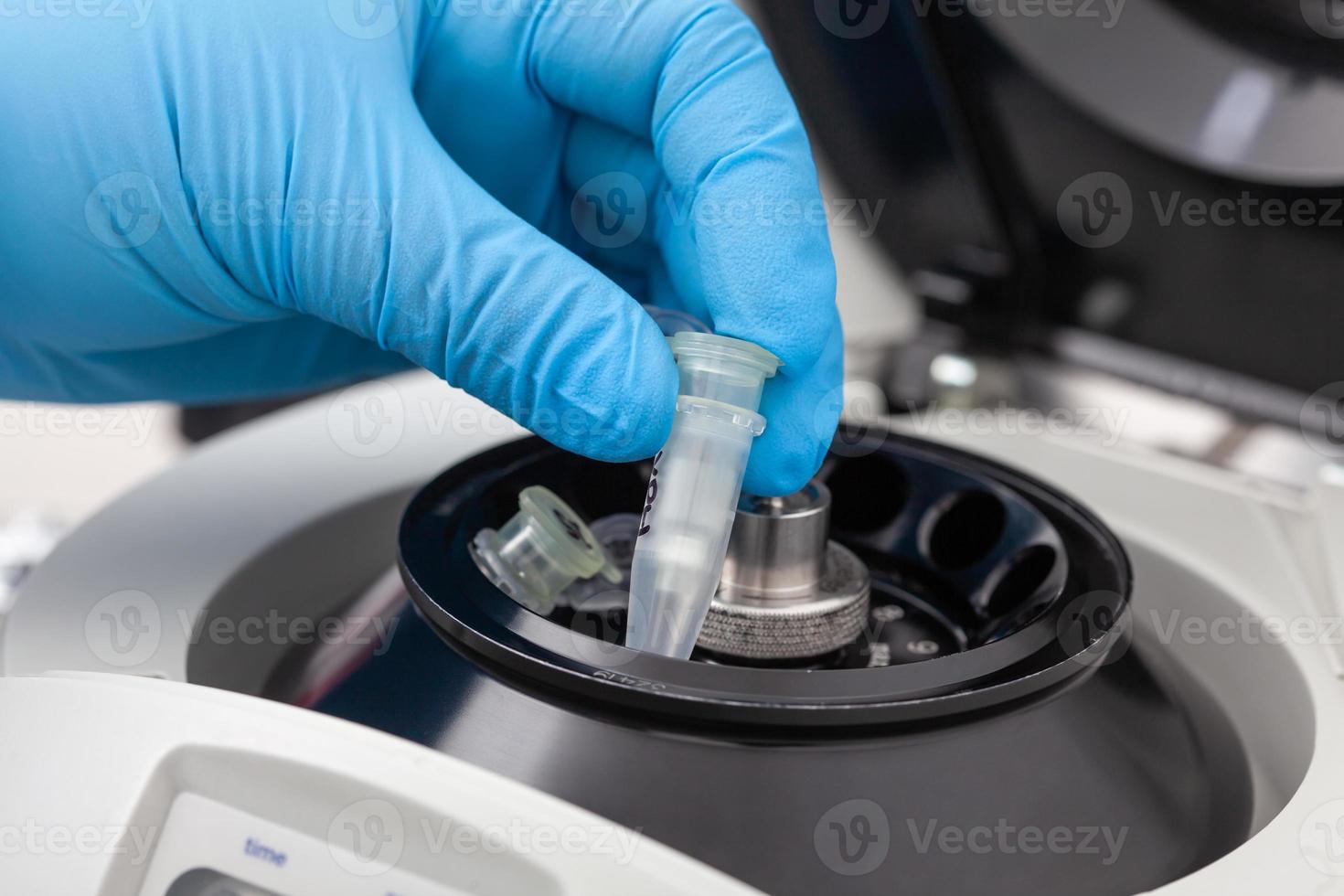 Closeup of a scientist hand placing a tube into an small table centrifuge. Spin column-based nucleic acid purification technique. Diagnosis of human papillomavirus virus infection. photo