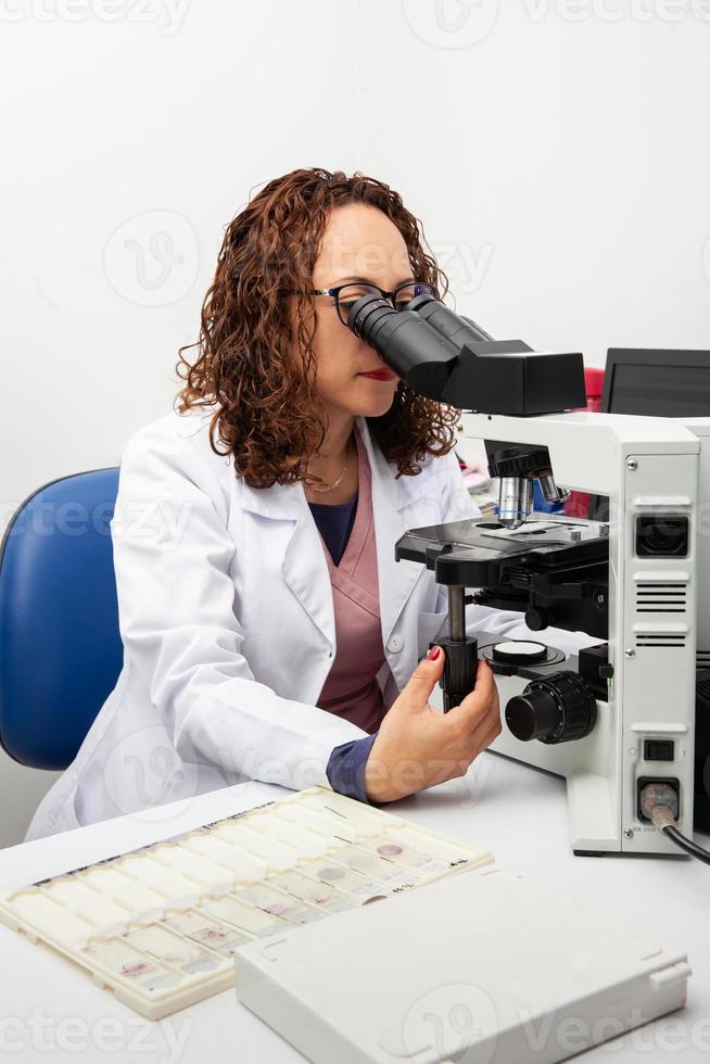 Cytologist looking at pap smear samples through a microscope. Medical analysis concept. Cervical cancer concept. photo