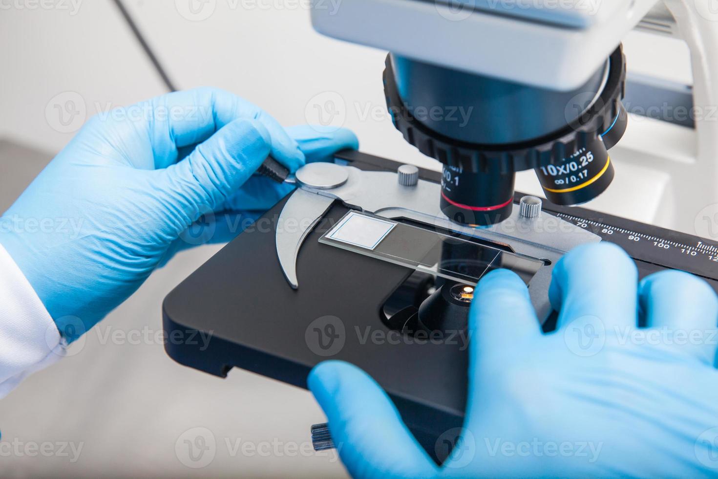 Young male scientist looking at slides under the microscope photo