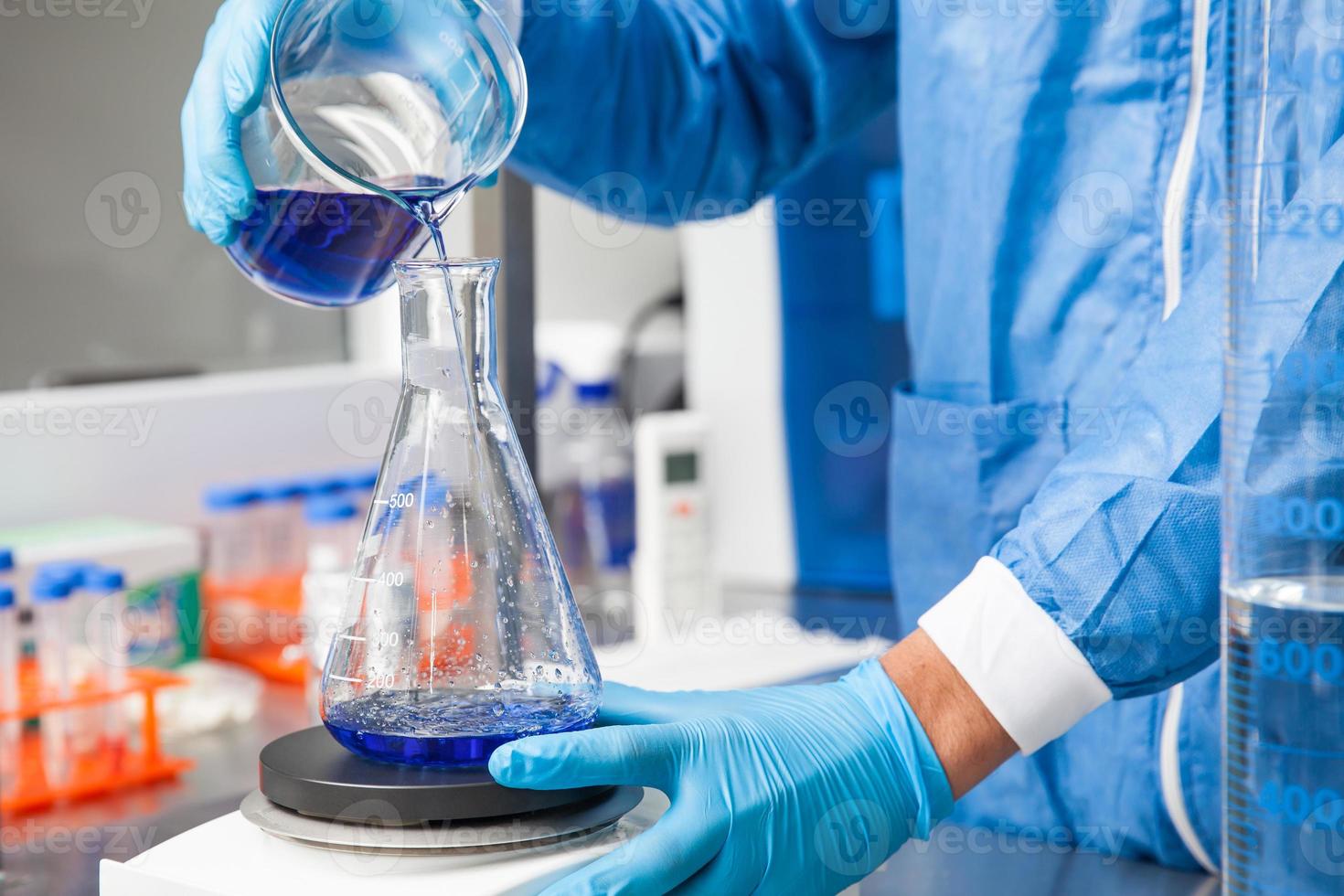 Young male scientist working with an stirrer at laboratory dressed in blue photo