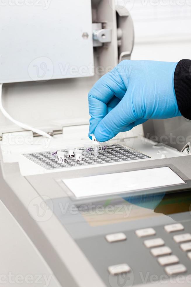 Closeup of a scientist hand while working at the laboratory with a thermal cycler. Polymerase chain reaction technique. PCR technique photo