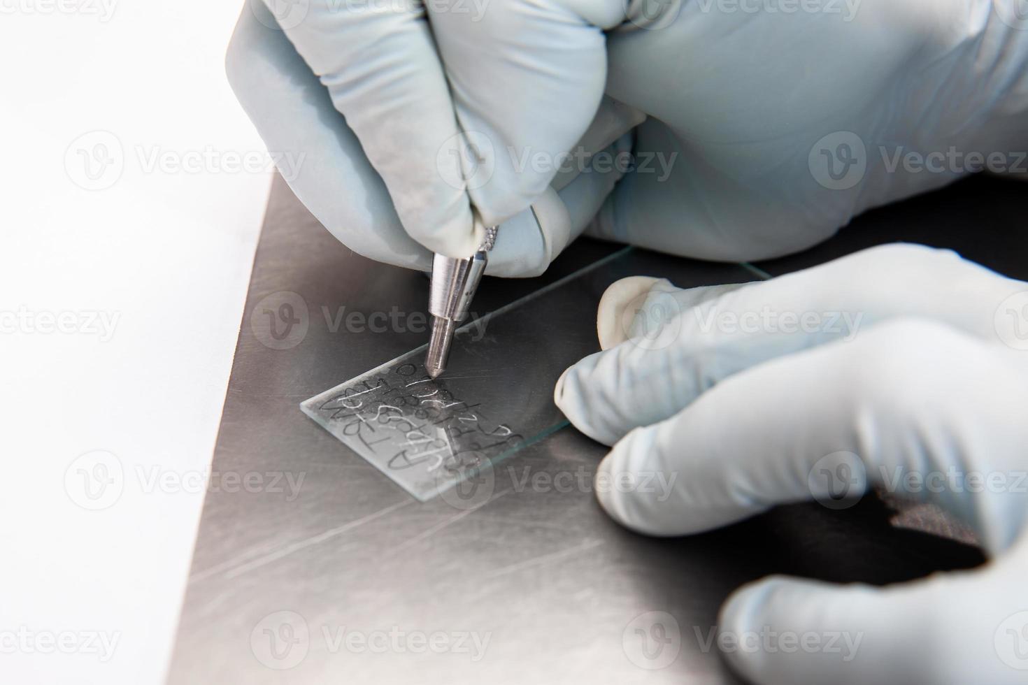 Laboratorian labelling a microscope slide using a diamond tip pencil. Laboratorian giving admission to pap smear samples in the laboratory for analysis. photo