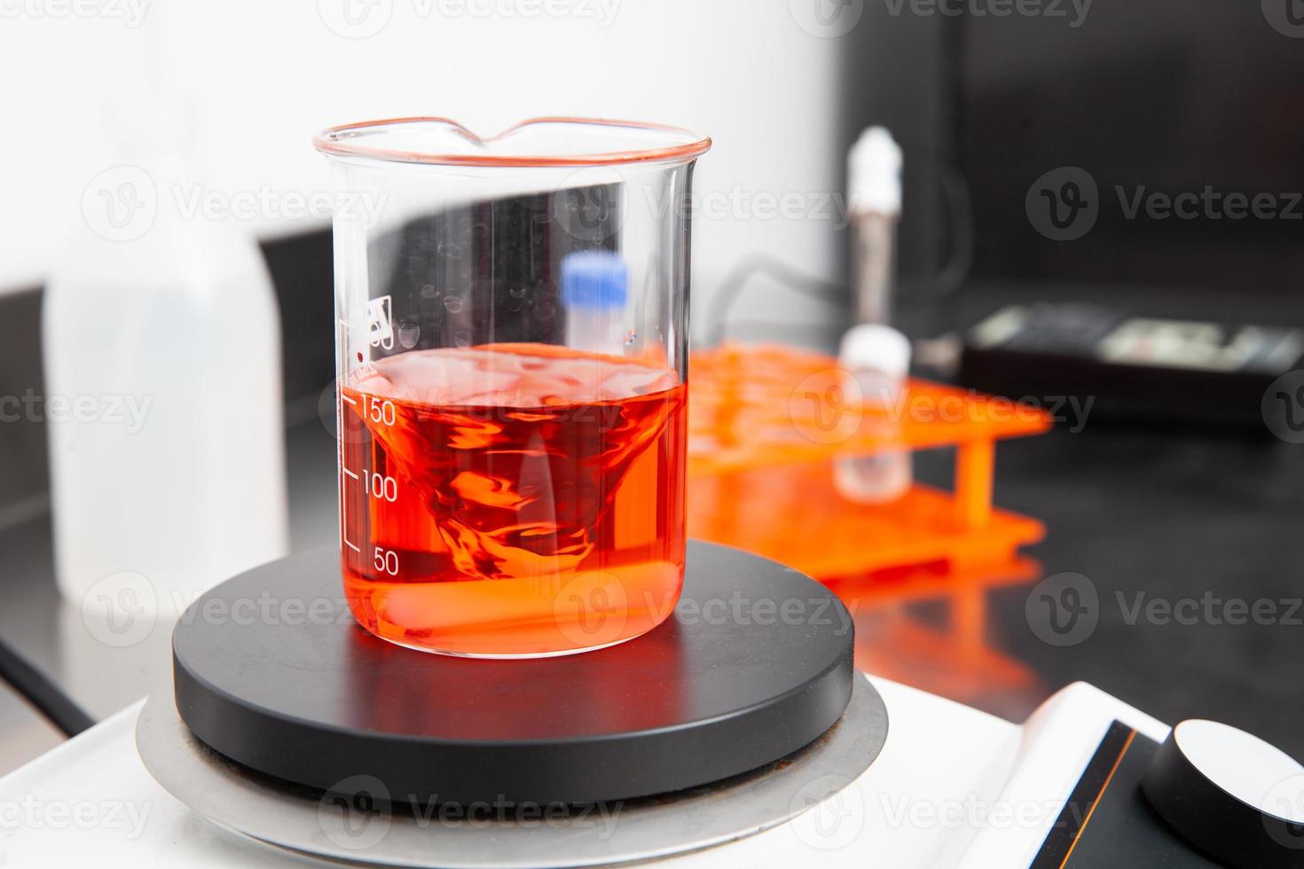 magnético agitador mezcla un líquido en un cubilete a laboratorio foto