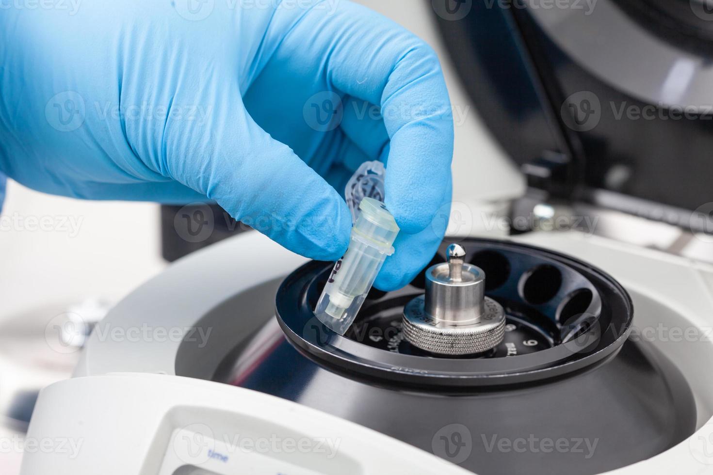 Closeup of a scientist hand placing a tube into an small table centrifuge. Spin column-based nucleic acid purification technique. Diagnosis of human papillomavirus virus infection. photo