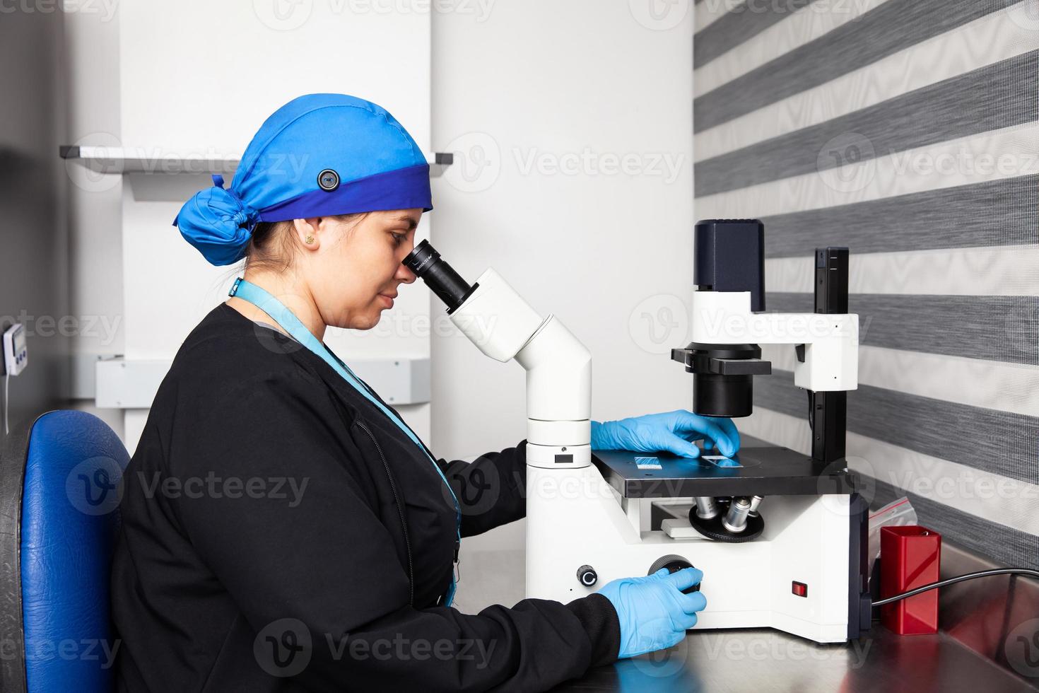 Female scientist looking at slides with patient samples using an inverted microscope in the laboratory. photo