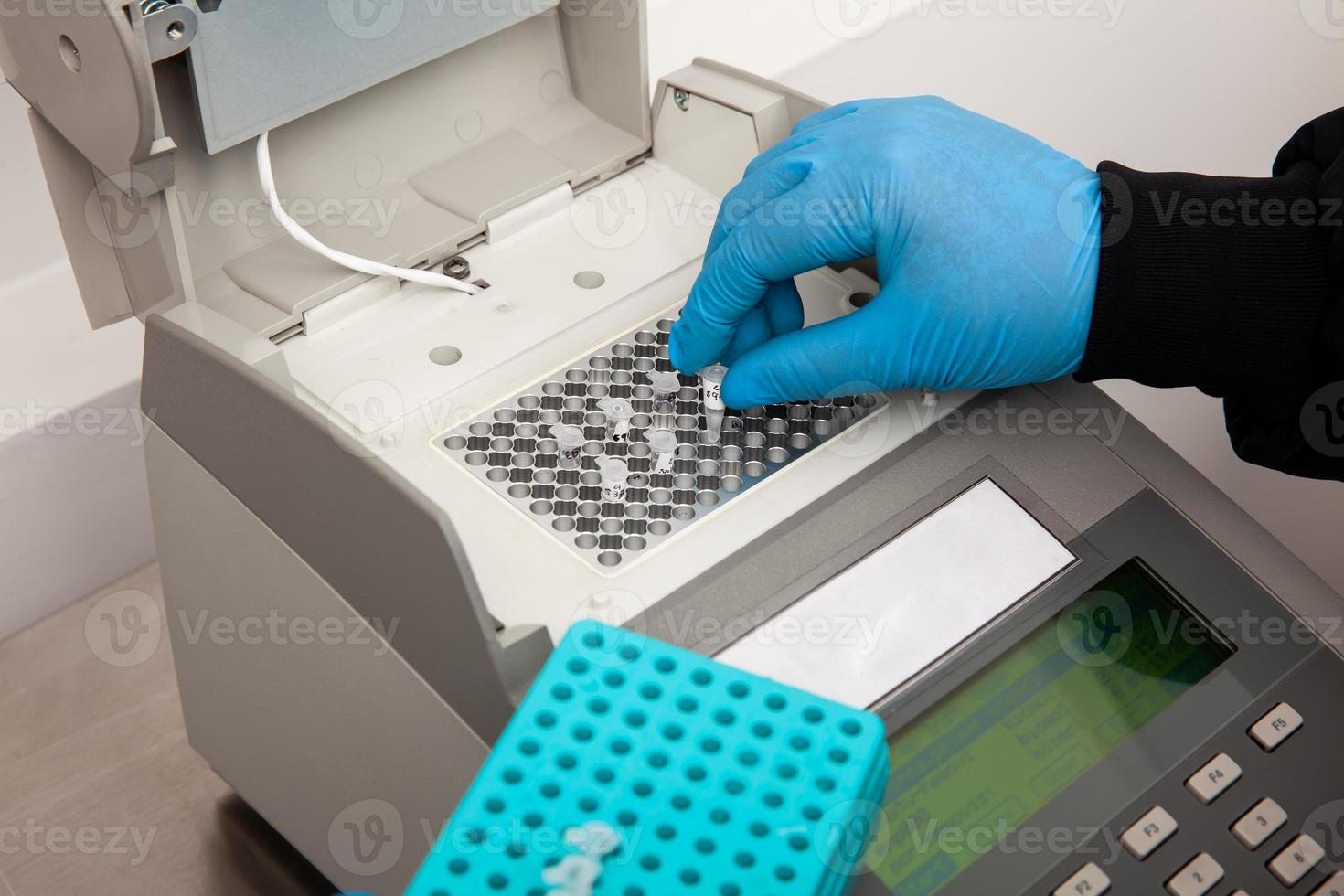 Closeup of a scientist hand while working at the laboratory with a thermal cycler. Polymerase chain reaction technique. PCR technique photo