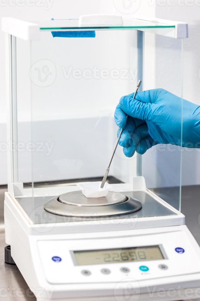 Scientist using an analytical balance at laboratory photo