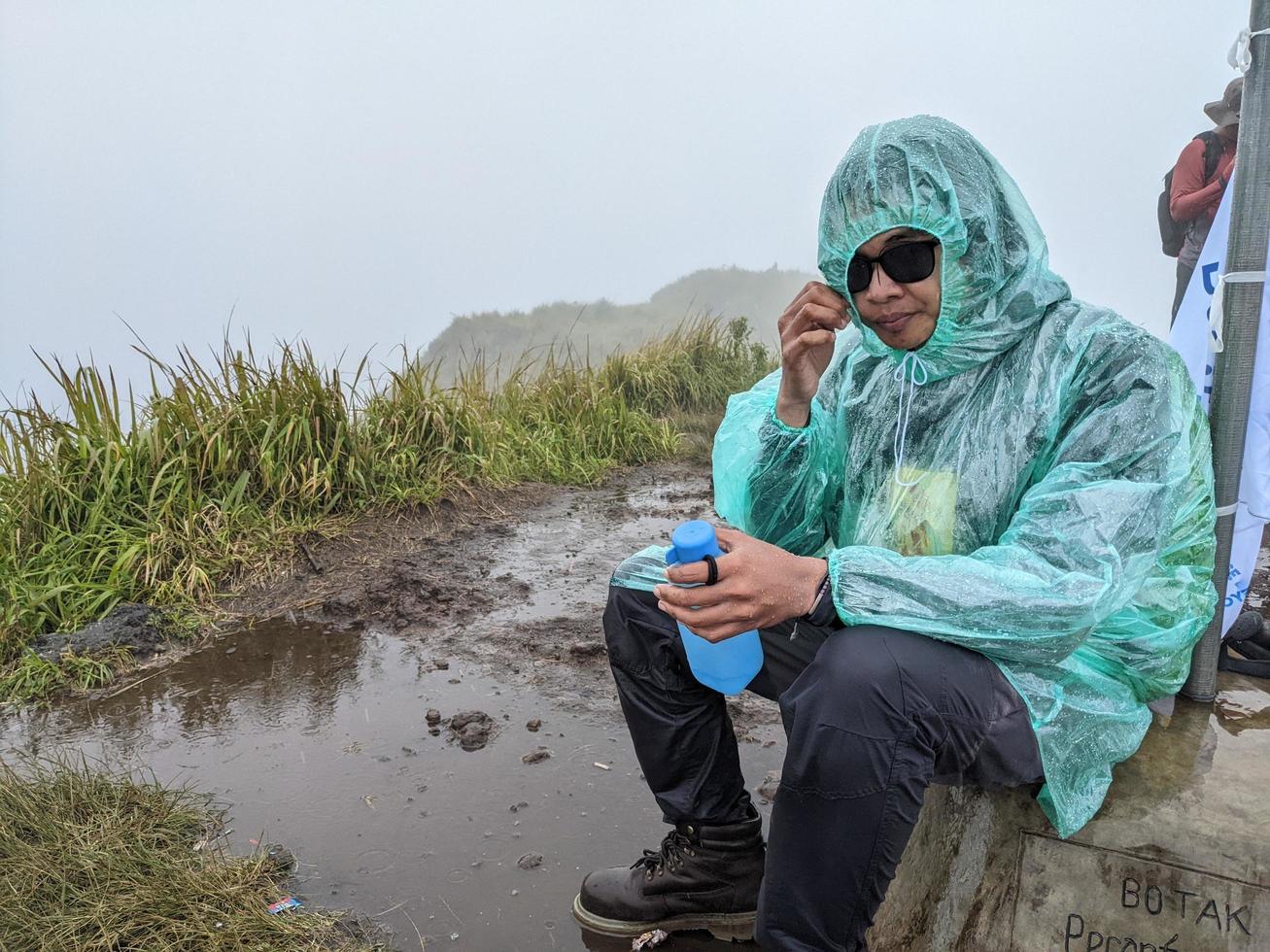 Man reach peak of mountain when rainy day with foggy vibes. The photo is suitable to use for adventure content media, nature poster and forest background.