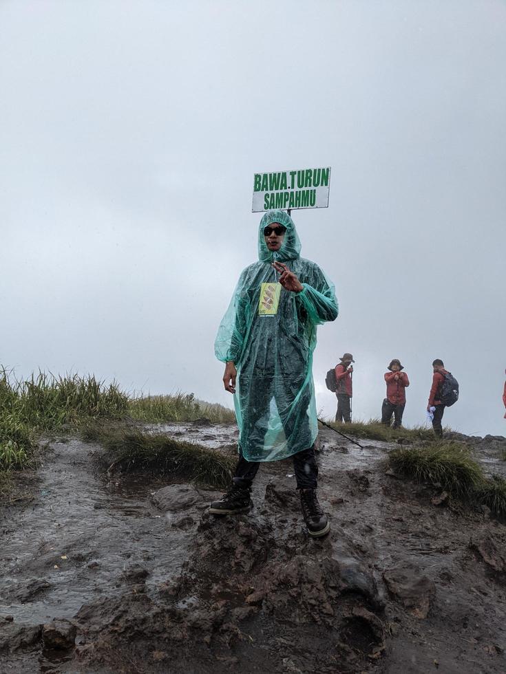 hombre alcanzar pico de montaña cuando lluvioso día con brumoso vibras. el foto es adecuado a utilizar para aventuras contenido medios de comunicación, naturaleza póster y bosque antecedentes.