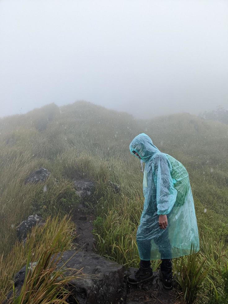 Man reach peak of mountain when rainy day with foggy vibes. The photo is suitable to use for adventure content media, nature poster and forest background.