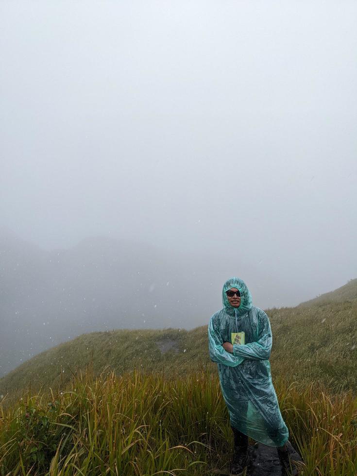 Man reach peak of mountain when rainy day with foggy vibes. The photo is suitable to use for adventure content media, nature poster and forest background.