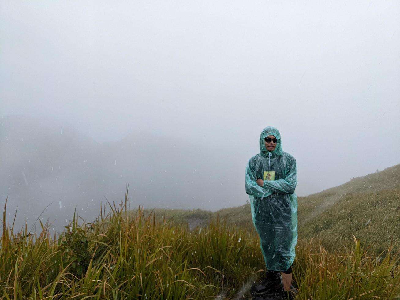 Man reach peak of mountain when rainy day with foggy vibes. The photo is suitable to use for adventure content media, nature poster and forest background.