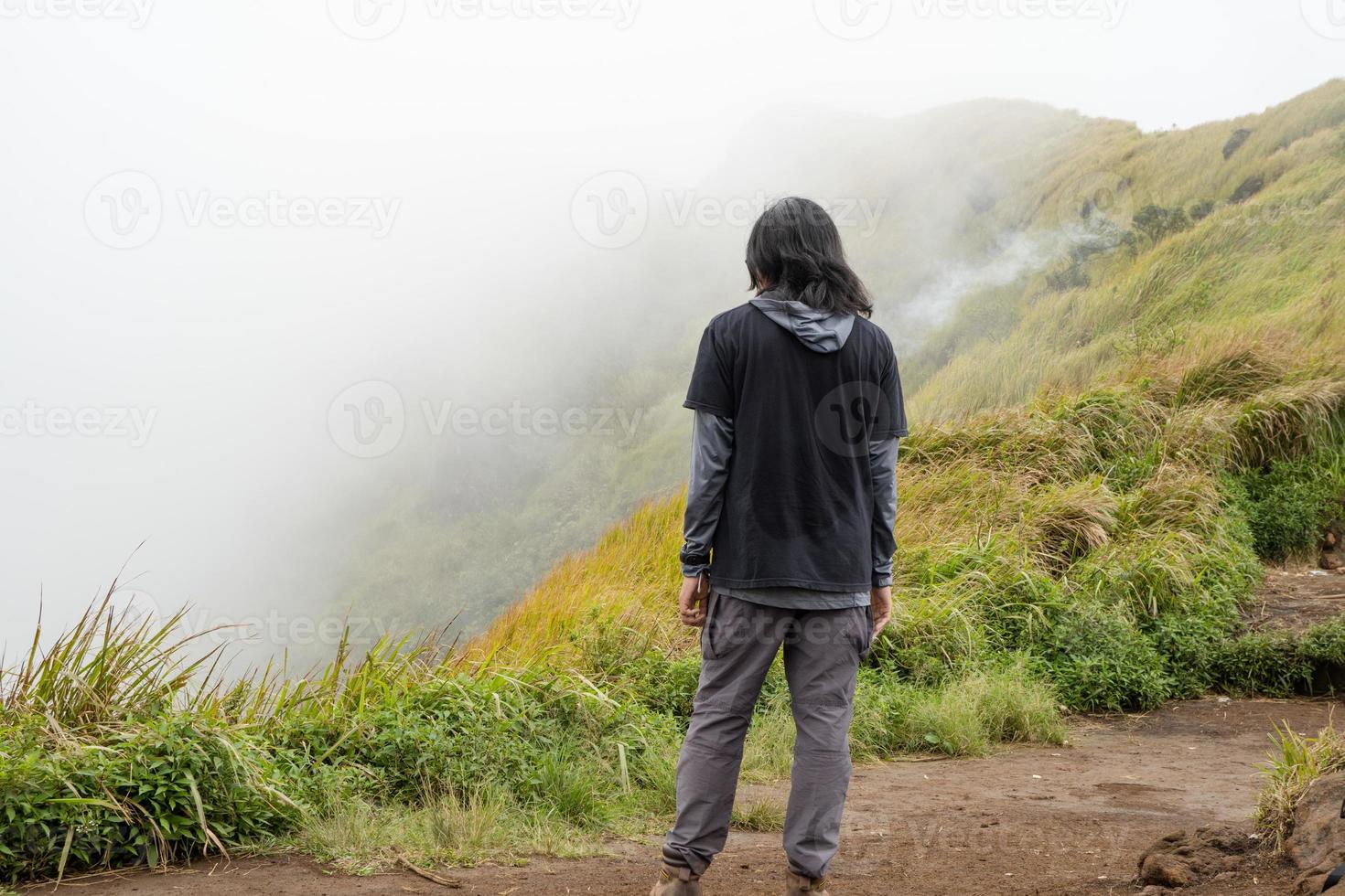 hombre excursionismo a el parte superior montaña, con savana pista y nublado vibras. el foto es adecuado a utilizar para aventuras contenido medios de comunicación, naturaleza póster y bosque antecedentes.