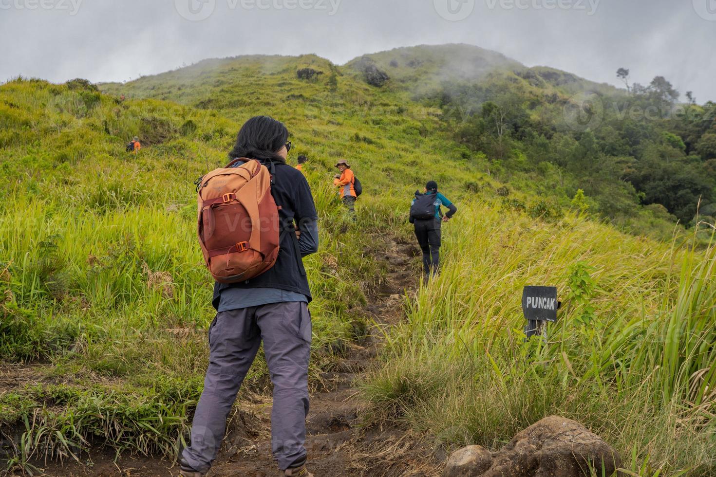 Man hiking to the top mountain, with Savana track and cloudy vibes. The photo is suitable to use for adventure content media, nature poster and forest background.