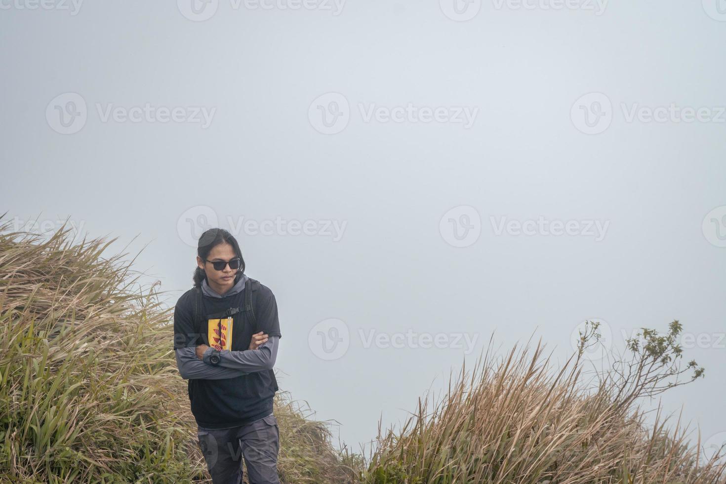 hombre excursionismo a el parte superior montaña, con savana pista y nublado vibras. el foto es adecuado a utilizar para aventuras contenido medios de comunicación, naturaleza póster y bosque antecedentes.