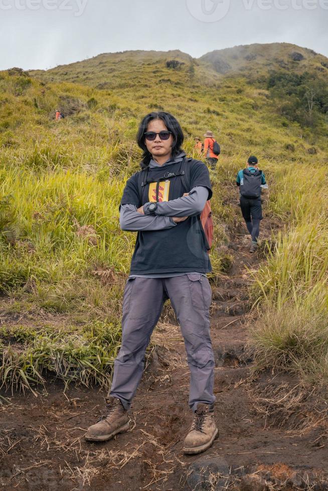 hombre excursionismo a el parte superior montaña, con savana pista y nublado vibras. el foto es adecuado a utilizar para aventuras contenido medios de comunicación, naturaleza póster y bosque antecedentes.