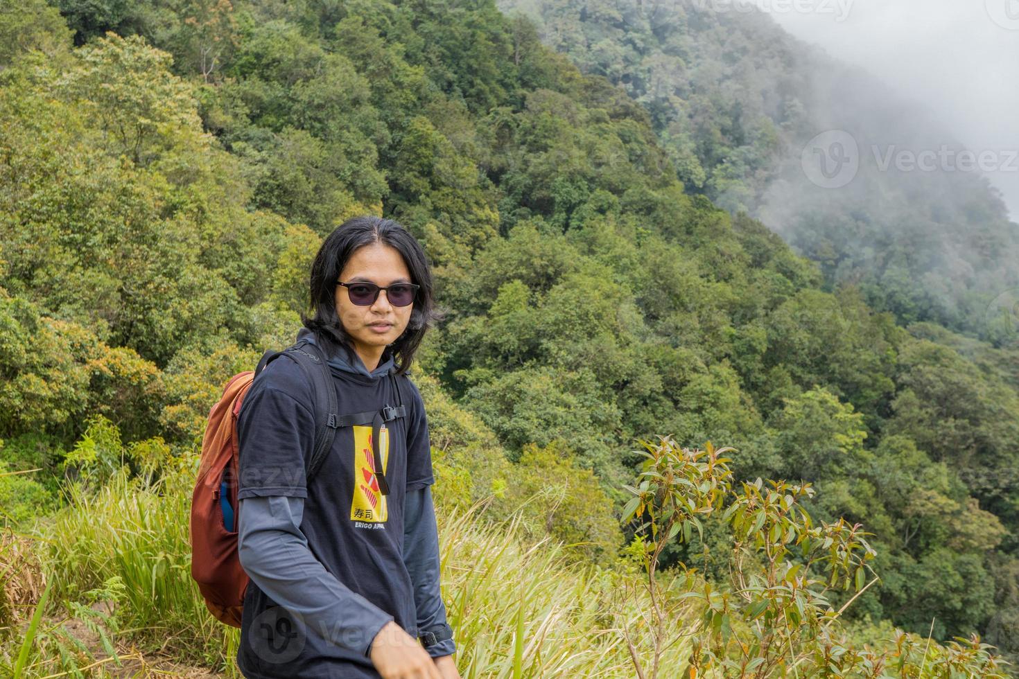 Man hiking to the top mountain, with Savana track and cloudy vibes. The photo is suitable to use for adventure content media, nature poster and forest background.