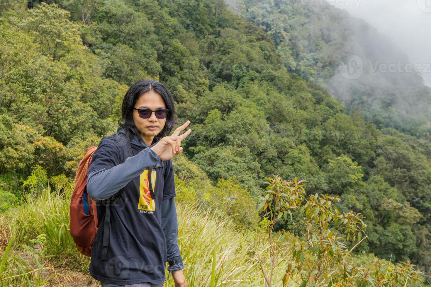 Man hiking to the top mountain, with Savana track and cloudy vibes. The photo is suitable to use for adventure content media, nature poster and forest background.