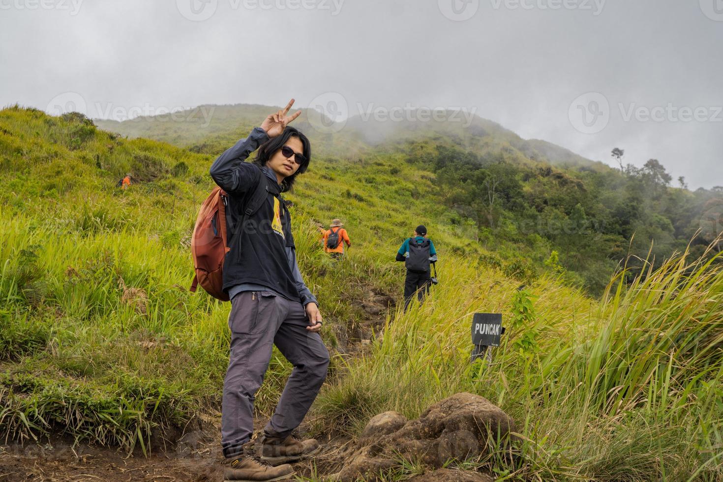 hombre excursionismo a el parte superior montaña, con savana pista y nublado vibras. el foto es adecuado a utilizar para aventuras contenido medios de comunicación, naturaleza póster y bosque antecedentes.