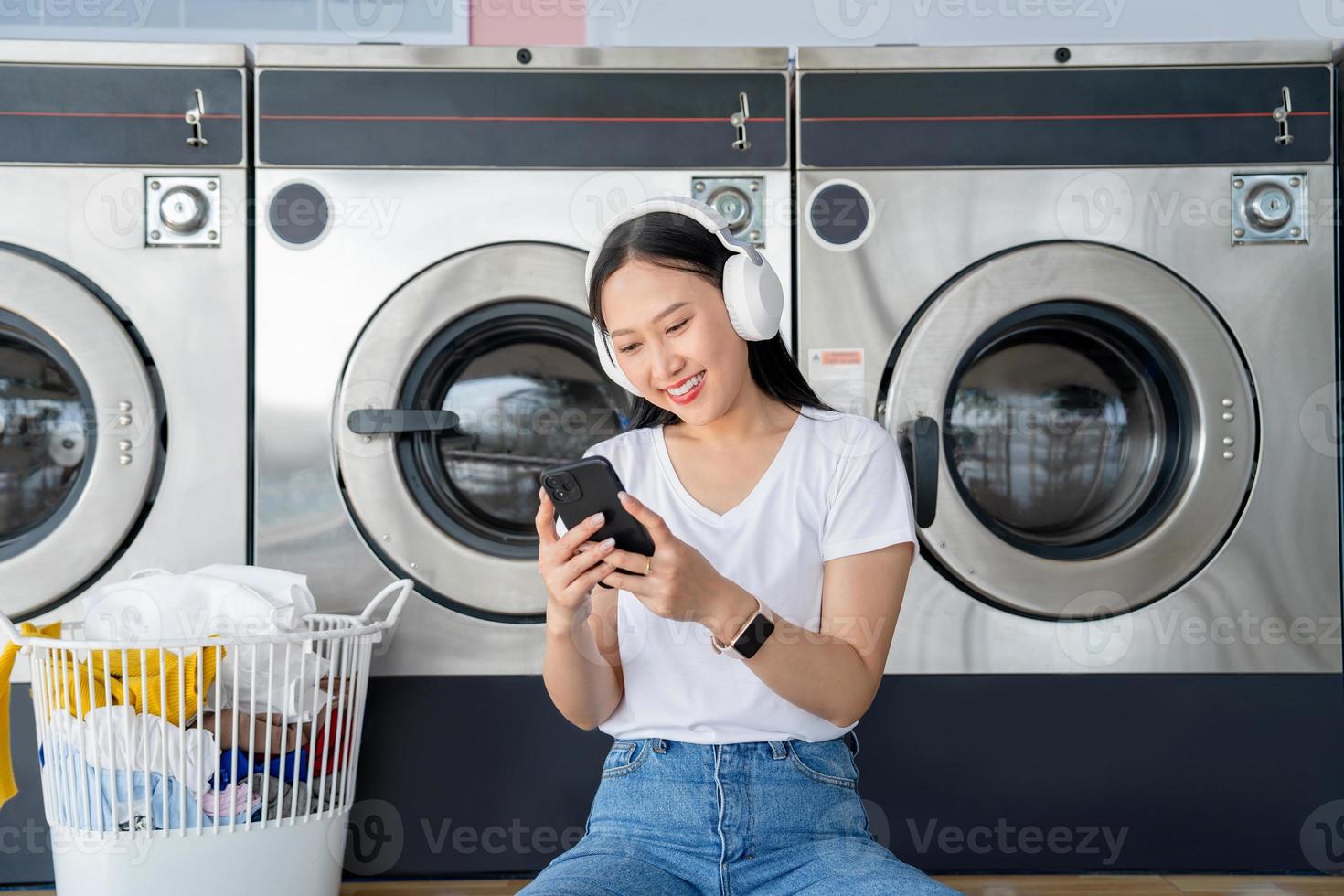 asiático mujer son escuchando a música a el lavandería tienda. foto