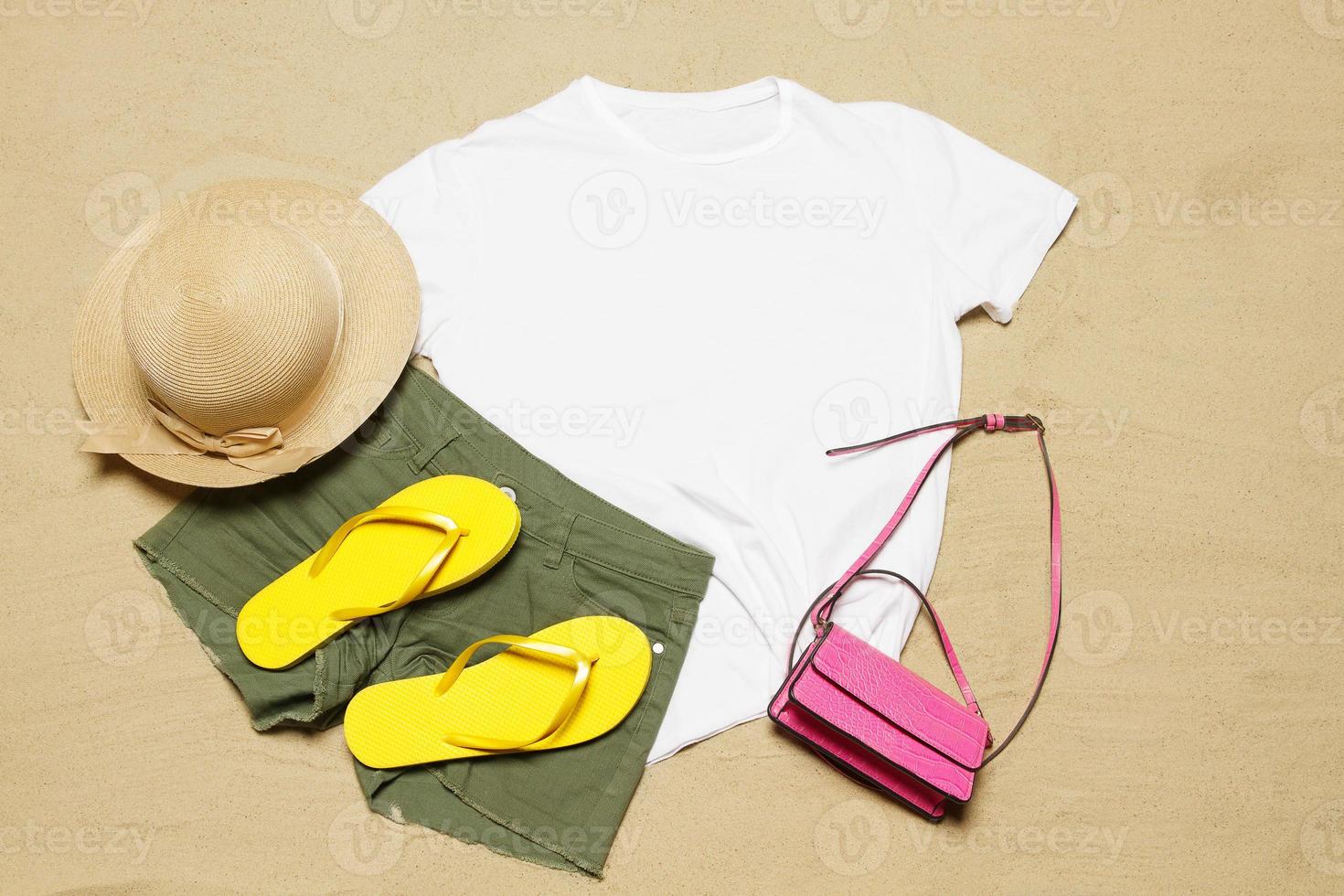 arena playa textura antecedentes. Bosquejo blanco verano camiseta Copiar espacio. blanco modelo mujer camisa parte superior vista. Hora de verano accesorios sombrero, chancletas, bolsa. aplanada de cerca camiseta en costa. tiempo de playa foto