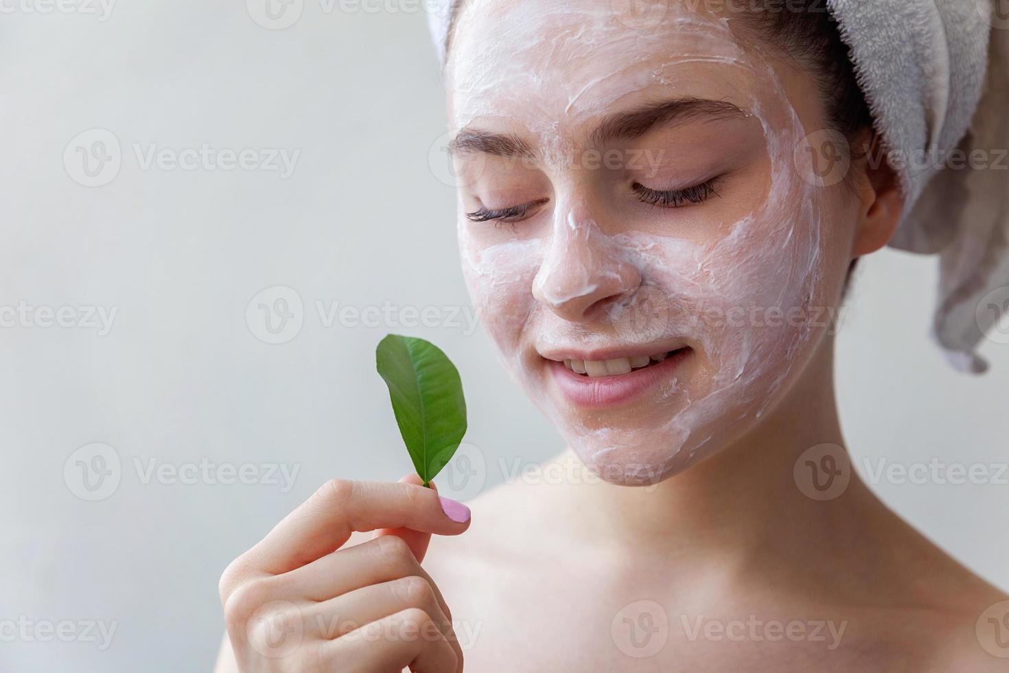 Woman face with green leaf and cream or nourishing mask photo