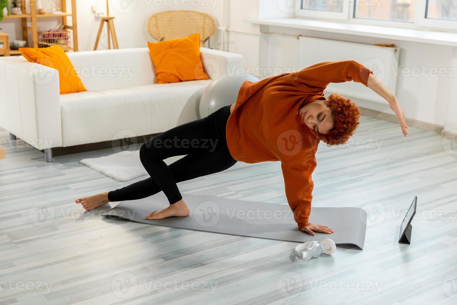 aptitud rutina de ejercicio capacitación. joven sano africano niña practicando yoga a hogar. mujer en ropa de deporte formación pilates haciendo Deportes ejercicio en yoga estera en piso interior. niña tener formación ejercicio. foto