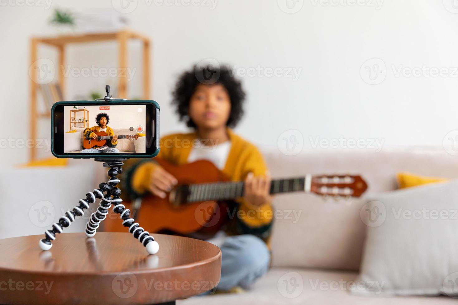 blogger guitarrista. africano americano niña blogger jugando guitarra hablando a cámara web grabación vlog. social medios de comunicación hombre de influencia mujer transmisión a hogar adentro. música contenido creador transmitir tutorial. foto