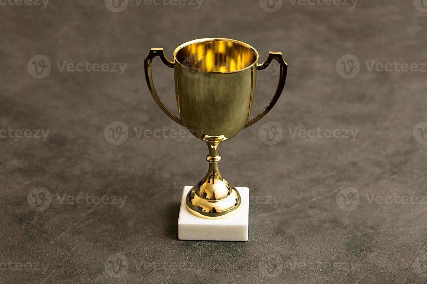 Simply design winner or champion gold trophy cup on concrete stone grey background. Victory first place of competition. Winning or success concept. Top view copy space. photo