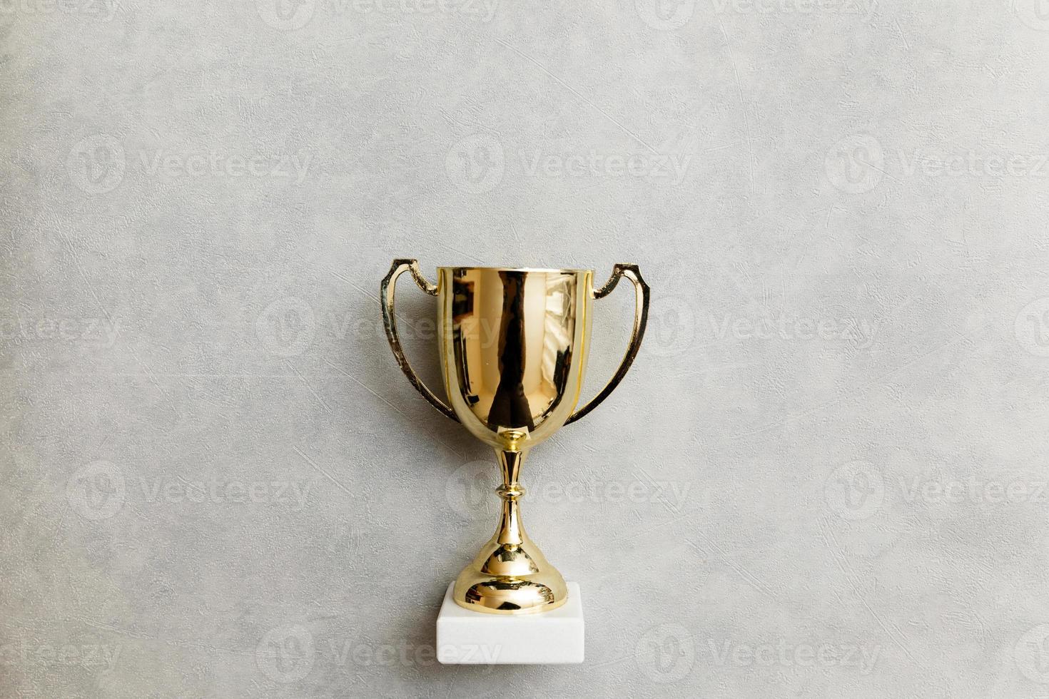 Simply flat lay design winner or champion gold trophy cup on concrete stone grey background. Victory first place of competition. Winning or success concept. Top view copy space. photo