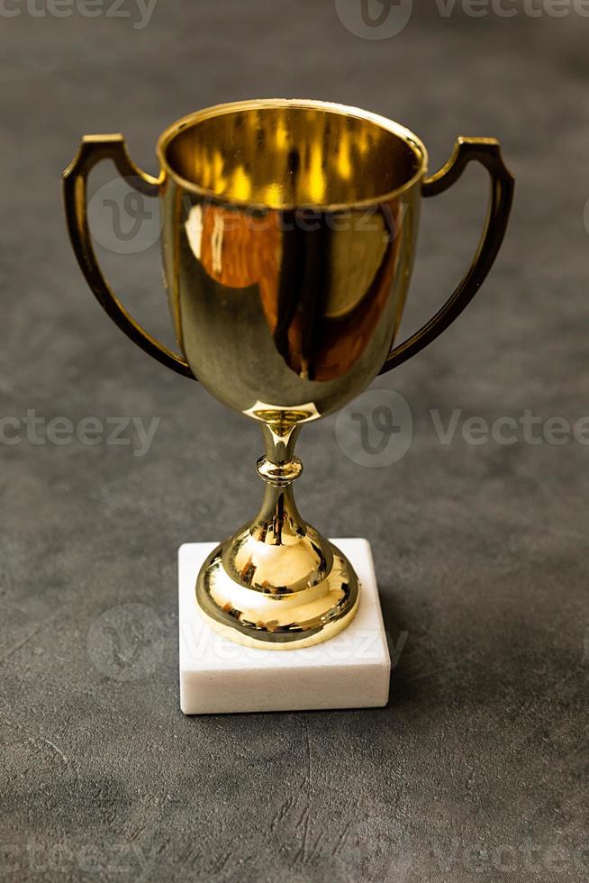 Simply design winner or champion gold trophy cup on concrete stone grey background. Victory first place of competition. Winning or success concept. Top view copy space. photo